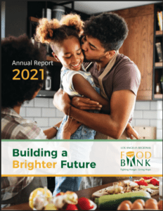 In a bustling kitchen, a person joyfully lifts a child as another looks on. The scene reflects the dedication of the Los Angeles Regional Food Bank, with text reading "Annual Report 2021" and "Building a Brighter Future.